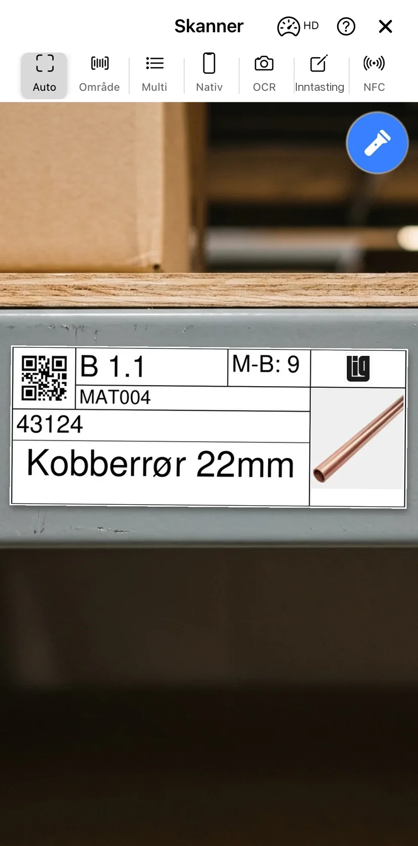 The mobile app scanner pointed at a printed QR label on a warehouse shelf